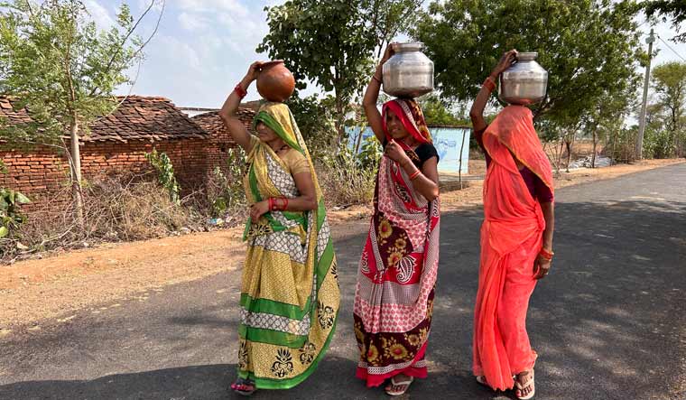 Women walk as they carry pitchers filled with drinking water in Lalitpur | AP