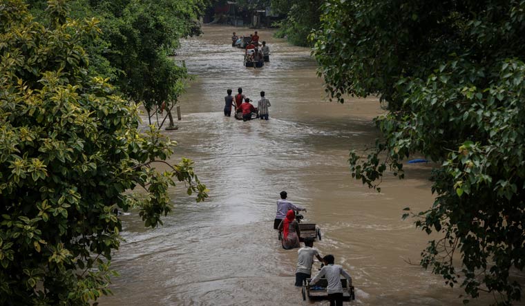 Residents carry their belongings on rickshaws through a street flooded with the rising water level of river Yamuna in Delhi | PTI