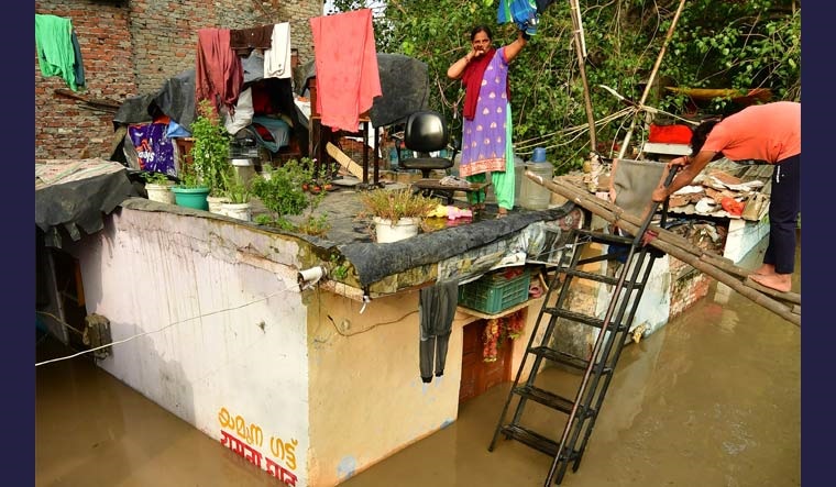 [File] A woman takes shelter on the roof of her house as the swollen Yamuna river inundates the area | Josekutty Panackal/Manorama