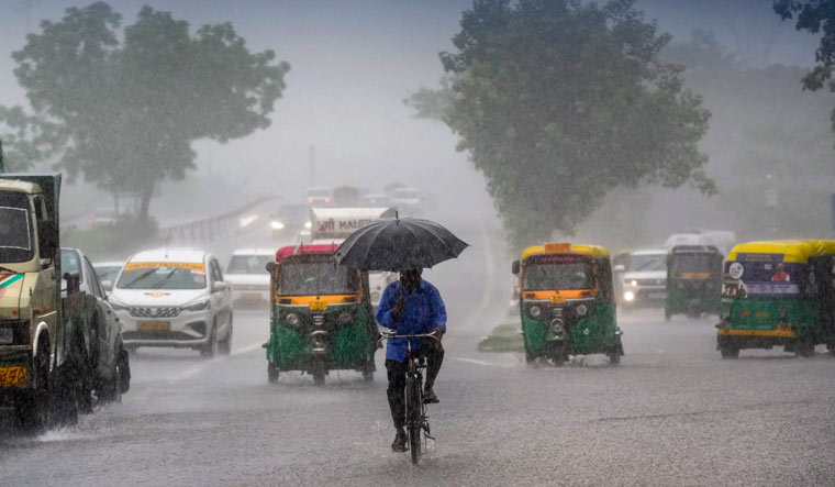 Commuters move past during monsoon rain in New Delhi | PTI
