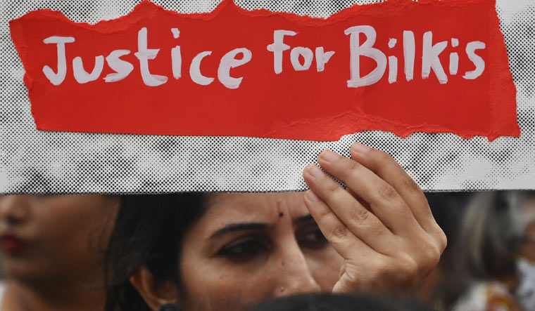 [File] A woman holds a placard during a protest against the release of men convicted of gang-raping Bilkis Bano | AFP