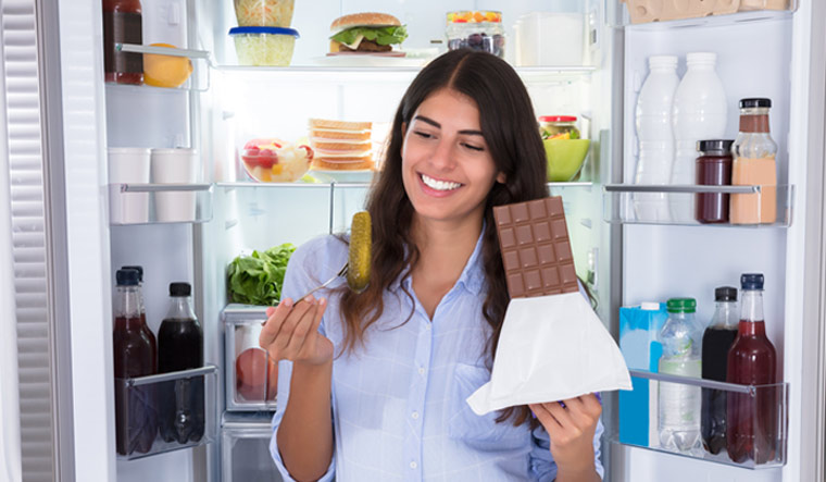night-Young-Woman-Eating-Chocolate-Near-Open-Refrigerator