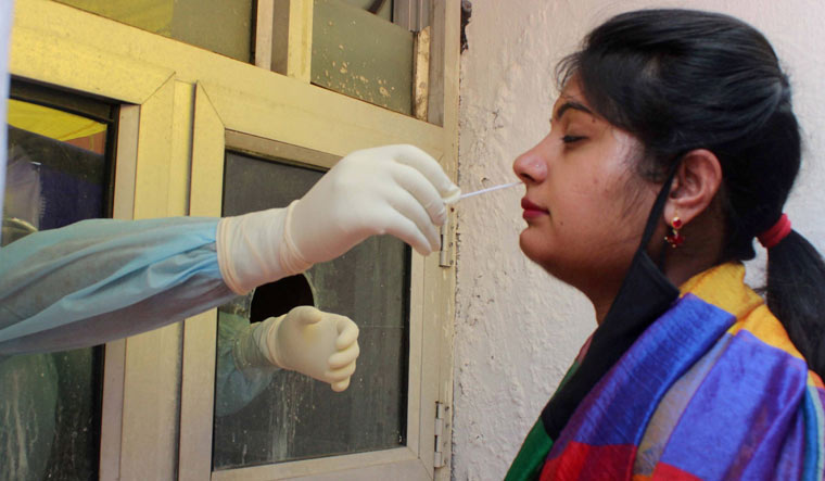 A medical worker collects a swab from a woman to test for the coronavirus disease at a hospital in Jammu | PTI