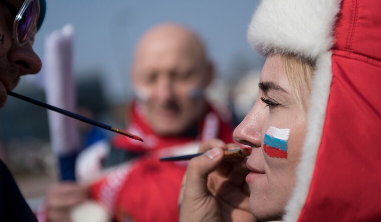 A fan gets her face painted with the Russia flag before the men's gold medal ice hockey match | AFP