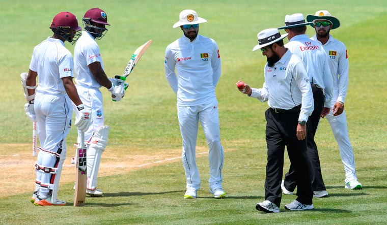 Dinesh Chandimal (centre) of Sri Lanka looks at the ball in umpire Aleem Dar's hand while Shai Hope (left) and Devon Smith (second left) of West Indies look on on day 3 of the second Test at Daren Sammy Cricket Ground, Gros Islet, St. Lucia | AFP