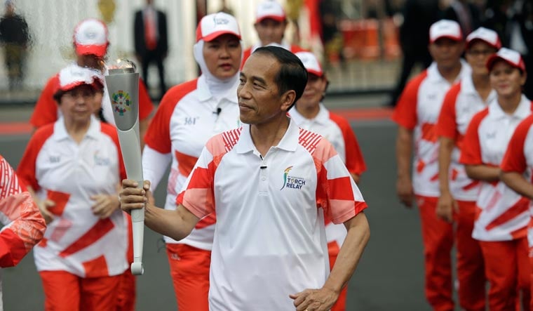Indonesian President JJoko "Jokowi" Widodo, center, holds the Asian Games torch as he runs during an independence day ceremony at Merdeka Palace in Jakarta, Indonesia on August 17 | AP