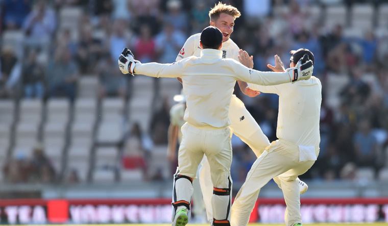 England's Sam Curran (C) celebrates with England's Jos Buttler (L) and England's Joe Root after trapping India's Ravichandran Ashwin leg before wicket (LBW) to win the test match on the fourth day of the fourth Test cricket match between England and India at the Ageas Bowl in Southampton