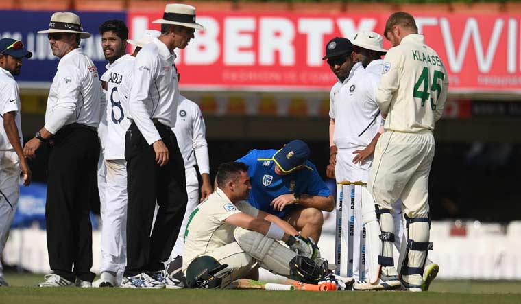 Dean Elgar (bottom centre) sits on the ground after being hit by a bouncer from Umesh Yadav (third left) on day 3 of the third and final Test match at the JSCA in Ranchi | AFP