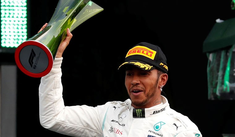 Mercedes' Lewis Hamilton celebrates on the podium with the trophy | Reuters