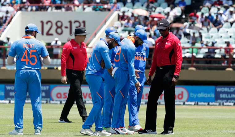 Indian players and umpires inspect the pitch after a rain stop during their first ODI against the West Indies in Providence, Guyana | AP