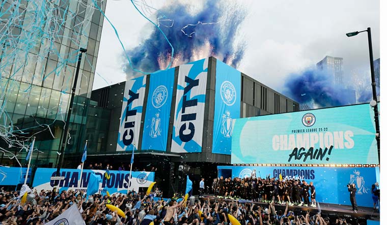 Flares and tape are let off as Manchester City's players celebrate on stage as fans watch the winners parade as the team celebrates winning the English Premier League title in Manchester, England, Monday, May 23, 2022 | AP