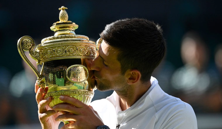 Novak Djokovic celebrates with the trophy after winning the men's singles final against Australia's Nick Kyrgios | Reuters