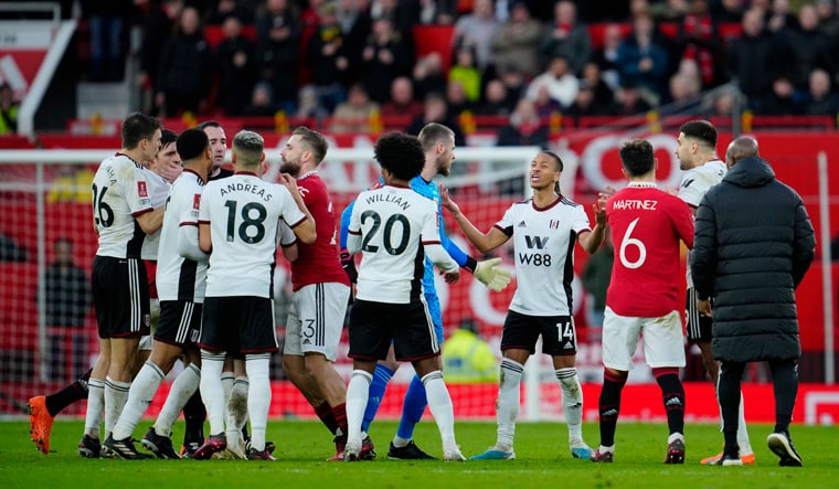 Players surround referee Chris Kavanagh, fourth left, after he showed red cards to Fulham's Aleksandar Mitrovic, second right, Willian, center left, and manager Marco Silva, during the English FA Cup quarterfinal soccer match between Manchester United and Fulham at the Old Trafford stadium in Manchester, England, Sunday, March 19, 2023. (AP Photo/Jon Super)