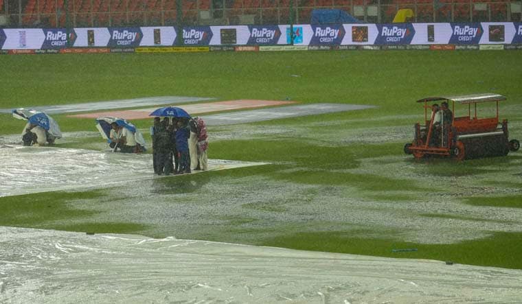 Ahmedabad: Groundsmen holding umbrellas near the covered pitch as it rains ahead of the IPL 2023 final cricket match between Gujarat Titans and Mumbai Indians at the Narendra Modi Stadium, in Ahmedabad, Sunday, May 28, 2023. (PTI Photo/Kunal Patil)  (PTI05_28_2023_000297B)