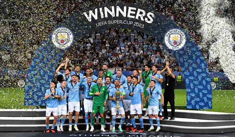 Manchester City players celebrate on the podium after winning the 2023 UEFA Super Cup final against Sevilla at the Georgios Karaiskakis Stadium in Piraeus | AFP