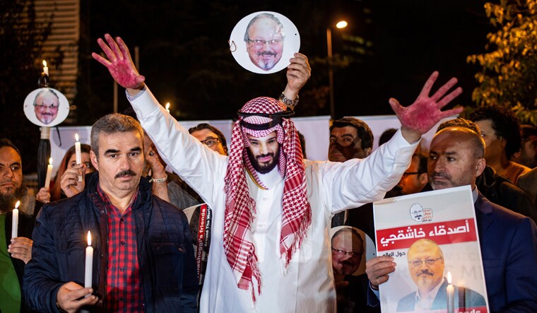 A protestor wears a mask of depicting Saudi Crown Prince Mohammad Bin Salman with red painted hands next to people holding posters of Saudi journalist Jamal Khashoggi during the demonstration outside the Saudi Arabia consulate in Istanbul | AFP