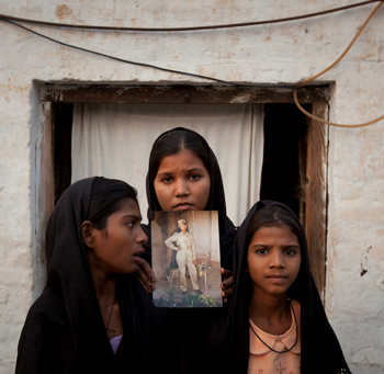 The daughters of Asia Bibi pose with an image of their mother while standing outside their residence in Sheikhupura located in Pakistan's Punjab Province | Reuters