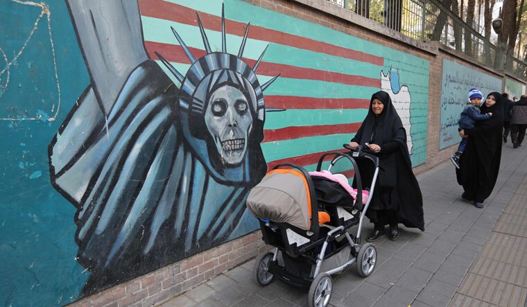 Iranian women walk past the walls of the former US embassy in Tehran on the 39th anniversary of the storming of the embassy by Islamic Revolution supporters | AFP
