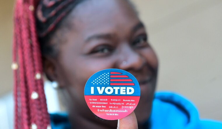 Shay Samuel displays her "I Voted" sticker after voting at a polling place inside the gymnasium at the Barack Obama Prep Academy in Los Angeles, California | AFP