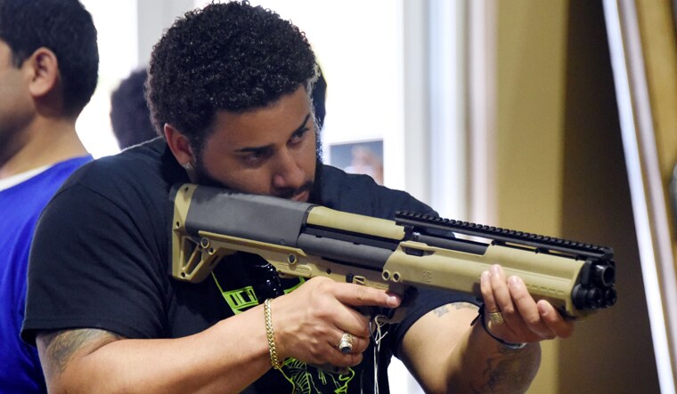 A gun enthusiast checks a weapon at the South Florida Gun Show at Dade County Youth Fairgrounds in Miami, Florida | AFP