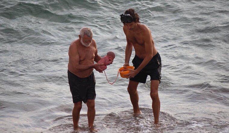 The man (left) carrying the newborn is said to be a doctor specialised in water births