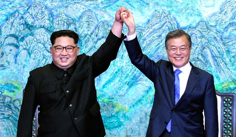 North Korean leader Kim Jong-un (left) and South Korean President Moon Jae-in raise their hands after signing a joint statement at Panmunjom | AP