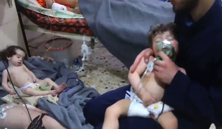 An image grab taken from a video released by the Syrian civil defence in Douma shows an unidentified volunteer holding an oxygen mask over a child's face at a hospital following a reported chemical attack on the rebel-held town on April 8, 2018 | AFP