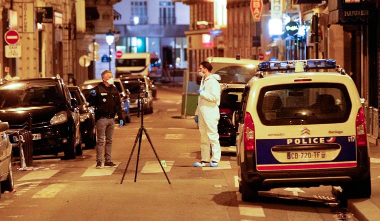 A forensic officer (R) and a French policeman (L) stand on Saint Augustin street in Paris after one person was killed and several injured by a man armed with a knife, who was shot dead by police | AFP