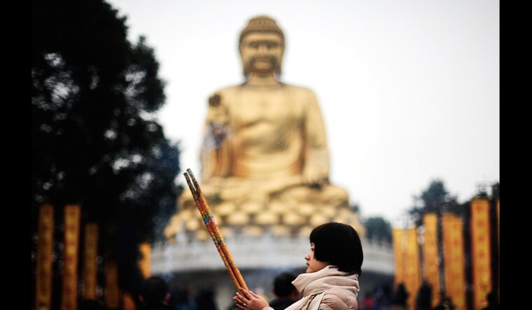 A worshipper offers prayer in front of a Buddha statue for her first visit of the year in Huayan Temple in southwest China's Chongqing Municipality | AP