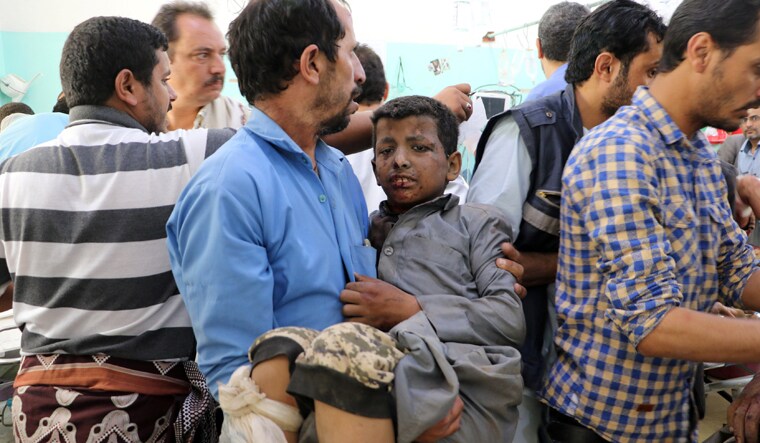 A Yemeni man holds a boy who was injured by an airstrike in Saada, Yemen | Reuters