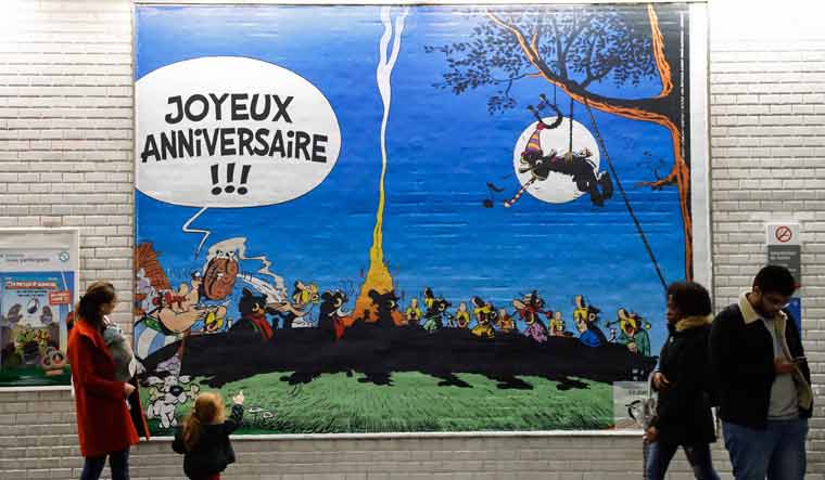 A child looks at a poster especially designed to commemorate the 60th anniversary of France's famous comic characters Asterix and Obelix | AFP