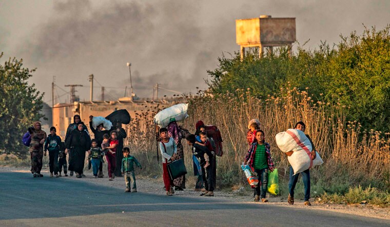 Civilians flee with their belongings amid Turkish bombardment on Syria's northeastern town of Ras al-Ain in the Hasakeh province along the Turkish border | AFP