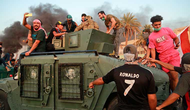 Anti-government protesters confront a soldier from the Federal Police Rapid Response Forces before they burn the armored vehicle, during a demonstration in Baghdad, Iraq | AP