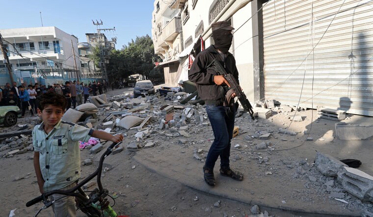 A Palestinian militant stands guard outside the home of Islamic Jihad field commander Baha Abu Al-Atta after it was hit by an Israeli strike | Reuters