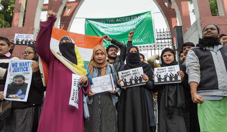 Protestors, including students and local residents, hold placards during a demonstration against the Citizenship Amendment Act (CAA), outside Jamia Millia Islamia University in New Delhi | PTI