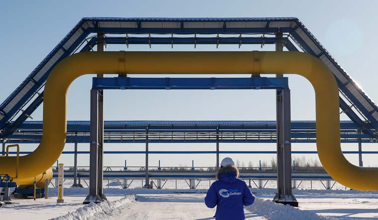 An employee in branded jacket walks past a part of Gazprom's Power Of Siberia gas pipeline at the Atamanskaya compressor station outside the far eastern town of Svobodny, in Amur region, Russia November 29, 2019 | Reuters