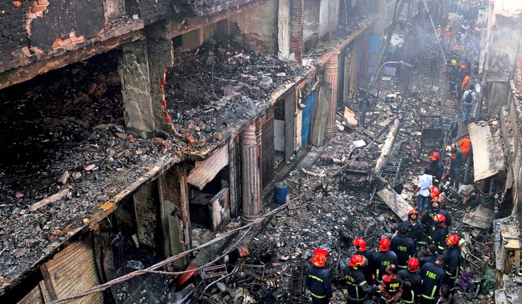 Locals and firefighters gather around buildings that caught fire late Wednesday in Dhaka, Bangladesh | AFP