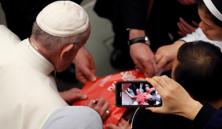 Pope Francis signs a banner from Chinese nuns and priests during the weekly general audience at Paul VI hall at the Vatican | Reuters