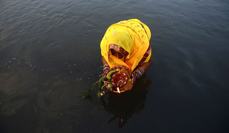 [File] A Nepalese Hindu woman makes offerings to the sun god in the Bagmati River in Kathmandu | AFP