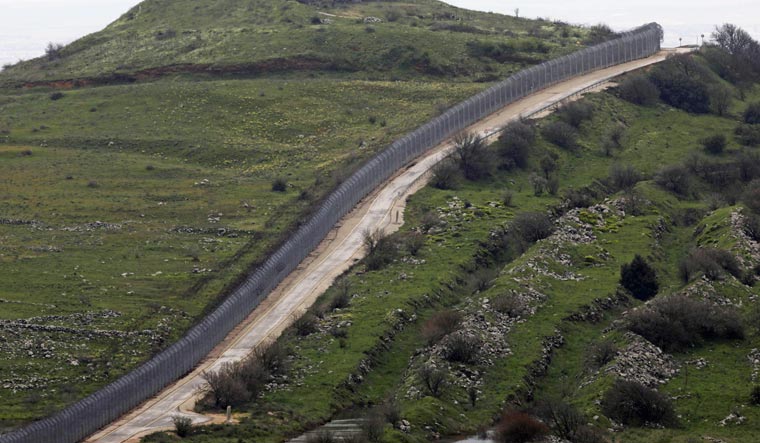 [File] A picture taken from the Israeli-annexed Golan Heights shows a view a fence separating the annexed territory from Syria | AFP