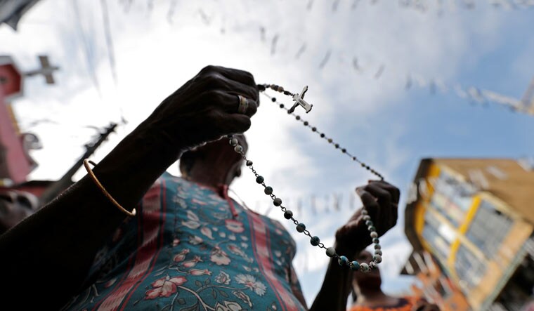 A woman holds a rosary during the silence observed as tribute to victims | Reuters
