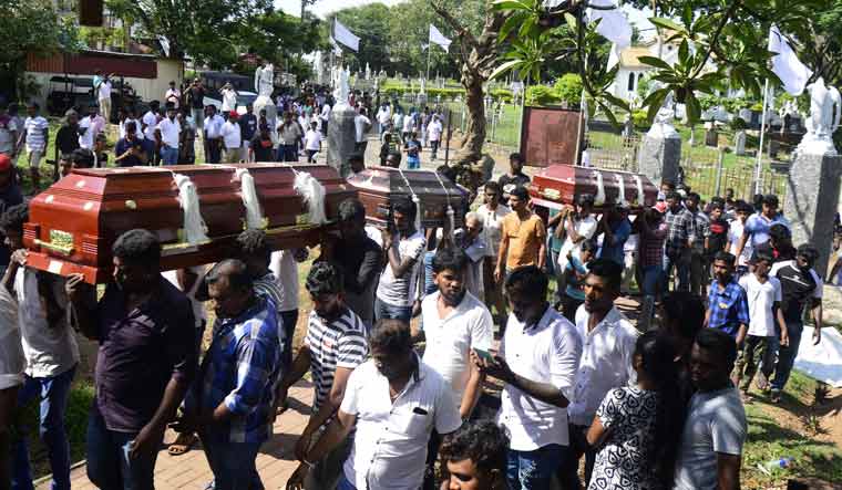 Relatives carry coffins of bomb blast victims during a funeral in a cemetery in Colombo | AFP