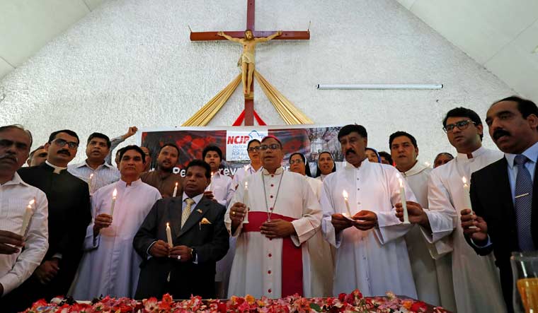 Bishop Joseph Arshad and Noordeen Mohamed Shaheid, High Commissioner of Sri Lanka to Pakistan, chant religious songs as they light candles to pay respect to the victims of Sri Lanka's serial bomb blasts | Reuters