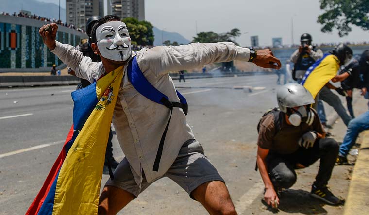 Supporters of Juan Guaido pelting stones against security personnel in Caracas during May Day commemoration | AFP