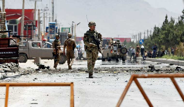 Afghan security forces and a British soldier with NATO-led Resolute Support Mission stand guard at the site of a suicide attack in Kabul | Reuters