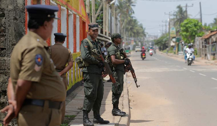 Sri Lankan army soldiers and police stand guard on a road in a Muslim neighborhood following overnight clashes in Poruthota, a village in Negombo | AP