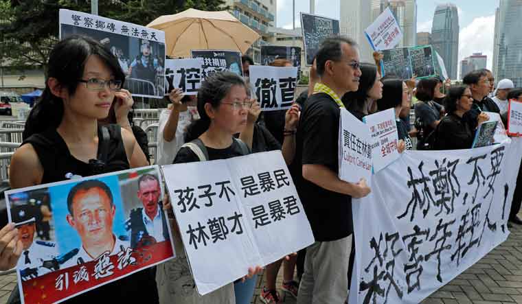 Activists from various groups including parents and religious hold placards of picture of police commander with Chinese reads "The child is not rioter, Carrie Lam is the tyrant", outside the government office demanding to stop shooting their kids in Hong Kong | AP