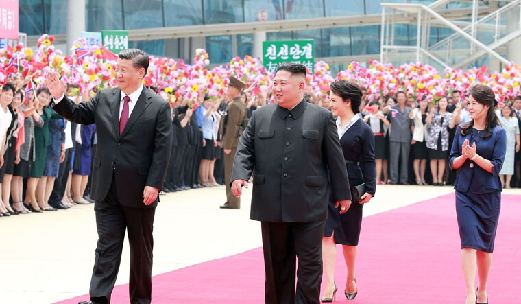 North Korean leader Kim Jong Un (C) walking with Chinese President Xi Jinping (L) upon his arrival at Pyongyang international airport | AFP
