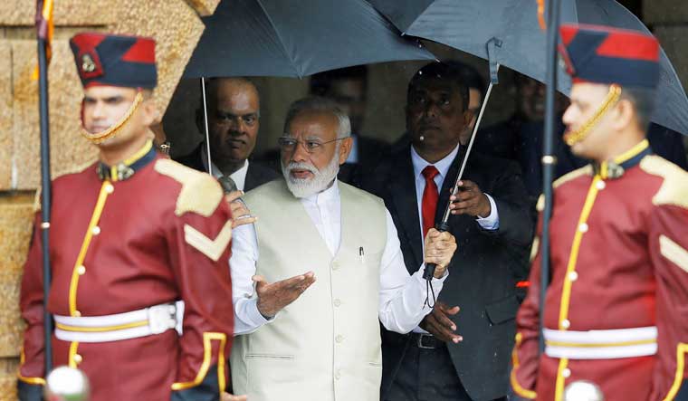 Prime Minister Narendra Modi holds an umbrella during his welcome ceremony at the Presidential Secretariat in Colombo | Reuters