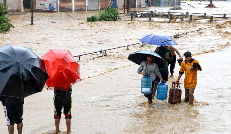 Nepali residents walk through floodwaters after the Balkhu River overflowed following monsoon rains at the Kalanki area of Kathmandu | AFP